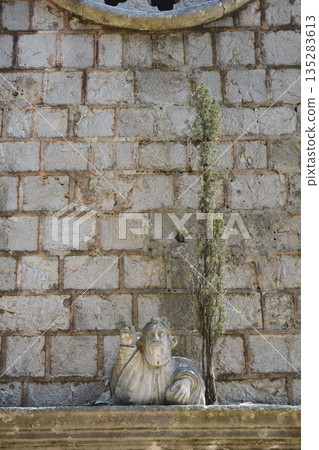 Stone statue and cypress detail on the facade of the Church of Our Lady of Mount Carmel 135283613