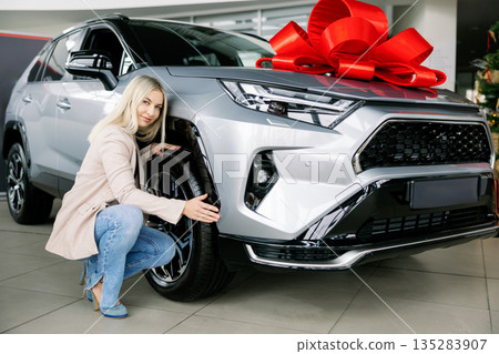 Woman checking new car tires in a dealership 135283907