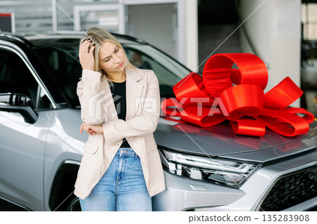 Thoughtful businesswoman choosing new car in dealership showroom 135283908
