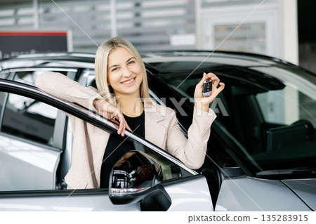Happy business woman showing car key in dealership 135283915