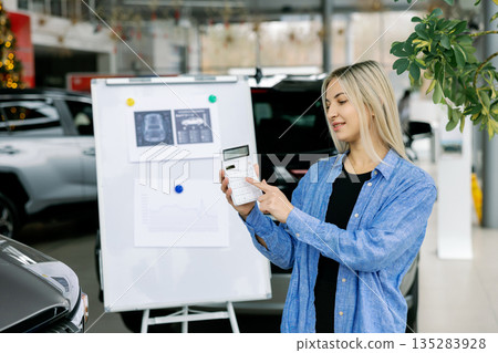 Saleswoman showing infographic during presentation about automotive suspension performance in car dealership 135283928