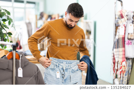 Young man choosing jeans in clothing store Young man choosing jeans in clothing store 135284027