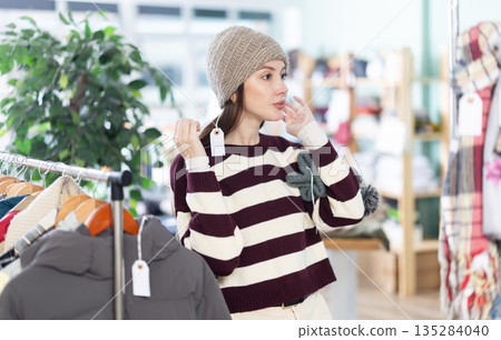 Female shopper chooses a hat in clothing store 135284040