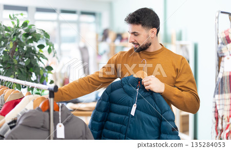 In store, man customer choose something outwear clothes In store, man customer choose something outwear clothes 135284053