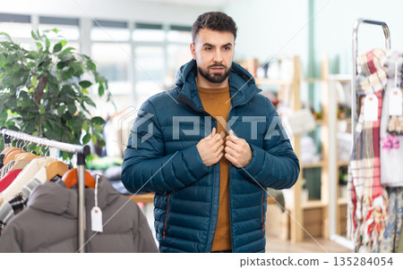 In store, man try on down jacket In store, man try on down jacket 135284054