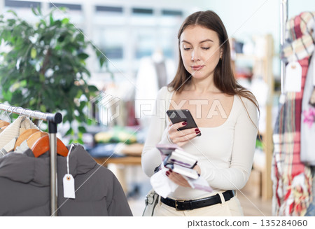 Female shopper checks quality of socks by scanning QR code on label 135284060