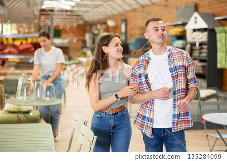 Spouses look for something in furniture store, searching for perfect item to complete patio 135284099