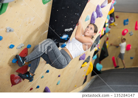 Young woman practicing rock climbing on climbing wall Young woman practicing rock climbing on climbing wall 135284147