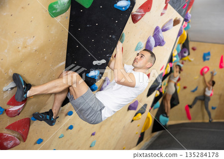 Young man practicing rock climbing on climbing wall 135284178