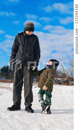 Brothers Holding Hands in Snowy Winter Day. Heartwarming moment of older and younger brothers standing together holding hands in fresh snow under bright blue sky. Sibling bond, family love and winter Brothers Holding Hands in Snowy Winter Day. Heartwarming moment of older and younger brothers standing together holding hands in fresh snow under bright blue sky. Sibling bond, family love and winter 135284188