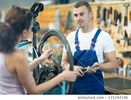 Male bicycle repair service worker consults client 135284196