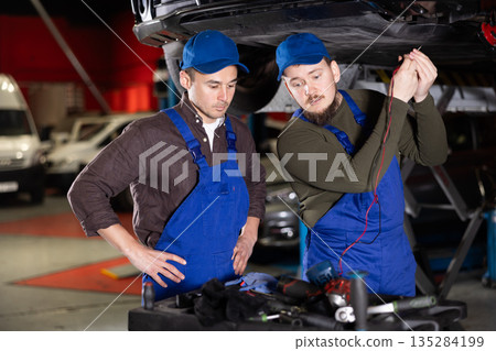Two mechanic guys checking car with measuring device 135284199