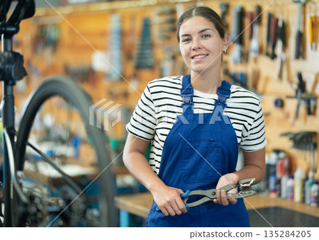 Young woman worker posing with bicycle tool Young woman worker posing with bicycle tool 135284205
