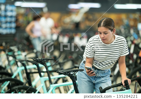 Young woman photographing bicycle in store 135284221