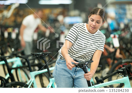 Young female choosing new bike with comfortable saddle in store 135284230