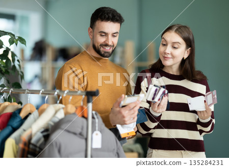 Young couple shoppers examining and buying new warm socks in clothing store Young couple shoppers examining and buying new warm socks in clothing store 135284231