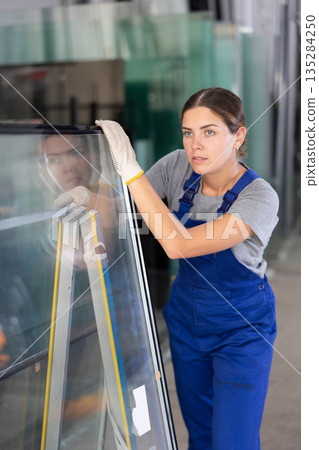 Female foreman inspecting plate glass cut to size 135284250