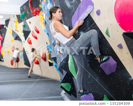 Young woman practicing rock climbing on climbing wall Young woman practicing rock climbing on climbing wall 135284309