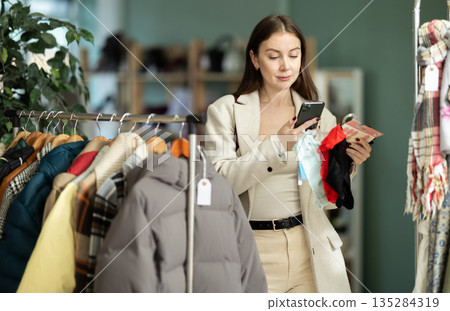 Young woman scanning QR-code on panties in clothing store Young woman scanning QR-code on panties in clothing store 135284319