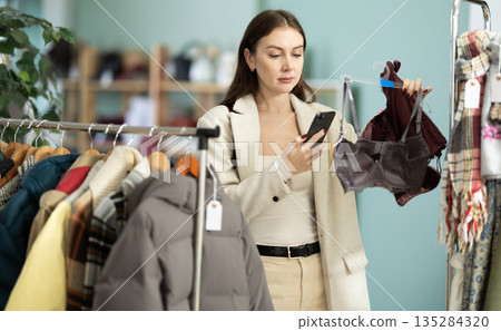 Female shopper checks quality of sexual bra by scanning QR code on label Female shopper checks quality of sexual bra by scanning QR code on label 135284320