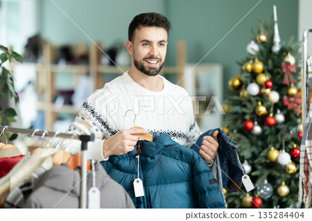 Man customer choose down jacket and jeans, X mas shopping Man customer choose down jacket and jeans, X mas shopping 135284404