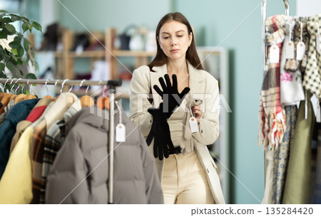 Young woman choosing gloves in clothing store 135284420