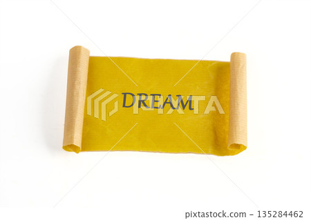 A vibrant, sun-kissed scroll gently unfurls, presenting the word DREAM emblazoned upon its surface, set against a pristine, stark backdrop 135284462