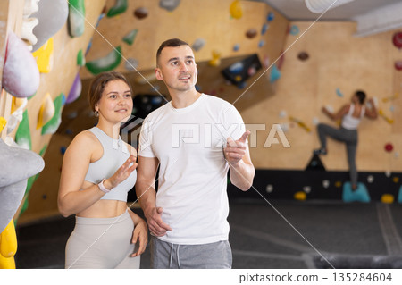 Girl gym coach and teen client standing in fitness room discussing possible options climbing 135284604