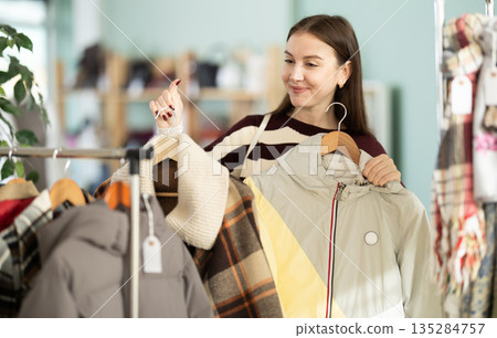 Young woman chooses jacket in clothing store Young woman chooses jacket in clothing store 135284757