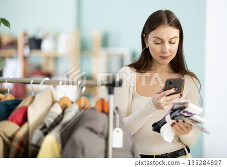 Female shopper checks quality of socks by scanning QR code on label Female shopper checks quality of socks by scanning QR code on label 135284897