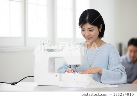 A middle-aged woman sewing in the living room 135284910