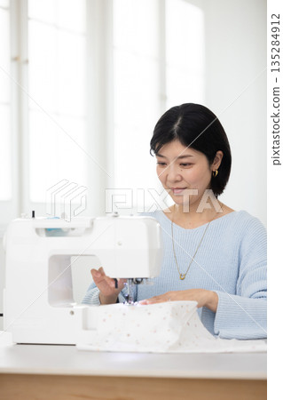 A middle-aged woman sewing in the living room A middle-aged woman sewing in the living room 135284912