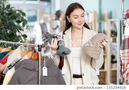 Female shopper chooses a hat in clothing store Female shopper chooses a hat in clothing store 135284916
