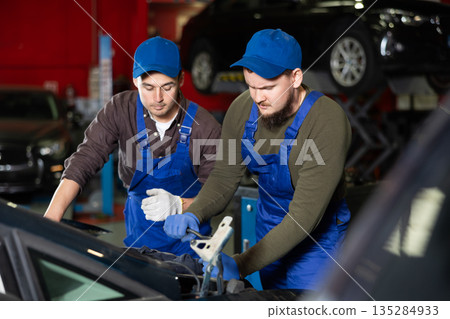 Two mechanic guys repairing car in car service Two mechanic guys repairing car in car service 135284933