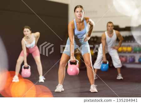 Young woman lifting kettlebell in gym Young woman lifting kettlebell in gym 135284941