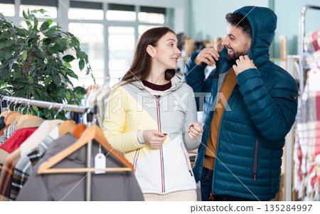 In store, couple try on down jacket 135284997