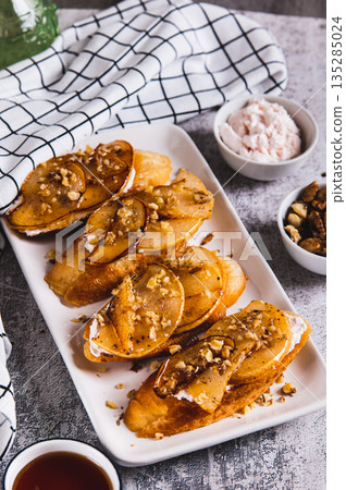 Delicious toasts with cream cheese, fried pear and honey on a plate on the table vertical view Delicious toasts with cream cheese, fried pear and honey on a plate on the table vertical view 135285024