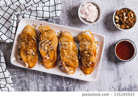 Sweet sandwiches with ricotta, baked pear, honey and nuts on a plate on the table top view 135285025
