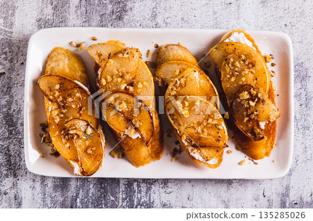 Close up of sweet sandwiches with ricotta, baked pear, honey and nuts on a plate top view Close up of sweet sandwiches with ricotta, baked pear, honey and nuts on a plate top view 135285026