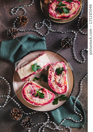 Savory rolls with herring under a fur coat  salad on a plate on the table top and vertical view 135285046