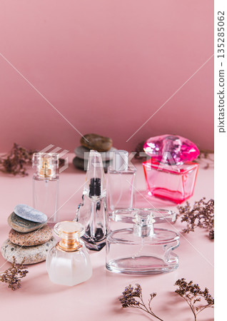 A beautiful arrangement of perfume bottles in pink tones on a table vertical view A beautiful arrangement of perfume bottles in pink tones on a table vertical view 135285062