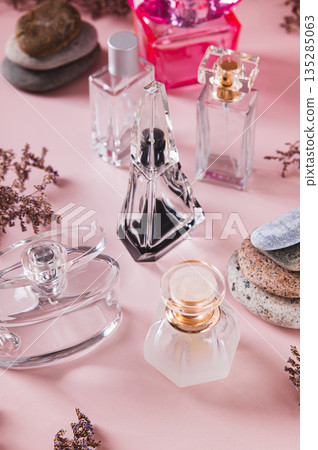 Perfume bottles, dried flowers and stones on a pink background vertical view Perfume bottles, dried flowers and stones on a pink background vertical view 135285063
