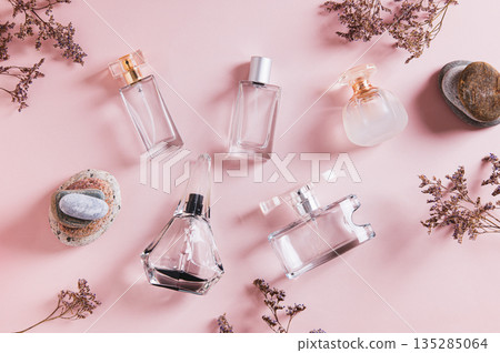 A beautiful arrangement of perfume bottles in pink tones on a table top view 135285064