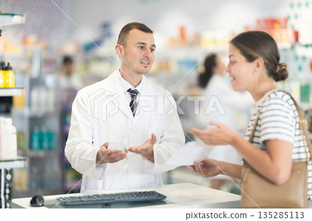Pharmacist giving prescription medicine to woman client Pharmacist giving prescription medicine to woman client 135285113