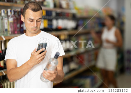 Young man scanning qr code for vodka 135285152