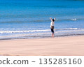 A woman refreshing herself on the beach facing the sea 135285160