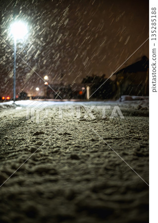 Snowfall and accumulation at night illuminated by street lights Snowfall and accumulation at night illuminated by street lights 135285188