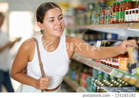 Young woman chooses sauce in store Young woman chooses sauce in store 135285192