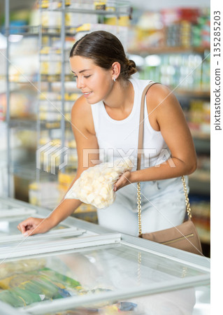 Girl supermarket visitor chooses frozen semi-finished products traditional Russian dumpling Girl supermarket visitor chooses frozen semi-finished products traditional Russian dumpling 135285203