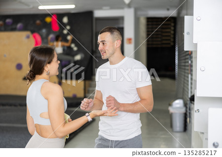 Climbing coach instructing female student by gym lockers before training 135285217